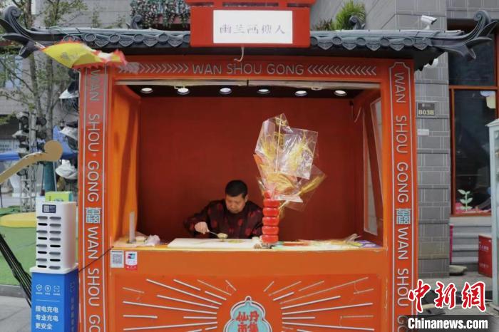 龔保新身著傳統(tǒng)服飾坐在自己的糖畫(huà)攤前進(jìn)行創(chuàng)作?！⒂駶?攝