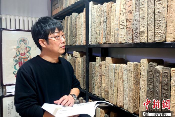 圖為謝濤對(duì)照書(shū)籍觀摩古磚?！「咪?攝