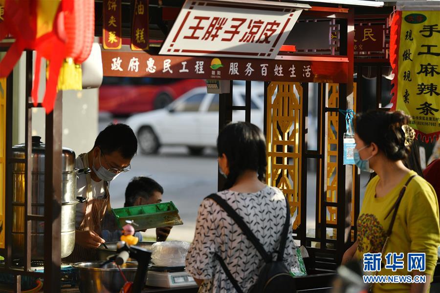 6月2日，在西安市曲江新區(qū)金滹沱二路，市民在臨時攤區(qū)選購食品。 近日，陜西省出臺《陜西省促進市場消費積極應(yīng)對新冠肺炎疫情影響若干措施》，在確保安全的情況下，允許城區(qū)臨街店鋪出店經(jīng)營，允許在居民居住集中區(qū)開辟臨時攤點攤區(qū)，允許流動商販在一定時間和區(qū)域占道經(jīng)營。 西安市曲江新區(qū)城市管理部門在做好疫情防控工作的前提下，在固定時間、固定區(qū)域開辟臨時攤點，積極推進“地攤經(jīng)濟”發(fā)展。 新華社記者 張博文 攝
