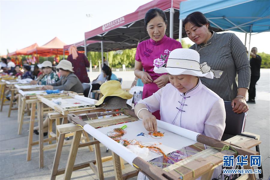 6月23日，民間刺繡藝人在現(xiàn)場展示刺繡技藝。 當日，全國最大的易地生態(tài)移民扶貧集中安置區(qū)寧夏吳忠市紅寺堡區(qū)舉行迎端午活動，邀請各鄉(xiāng)鎮(zhèn)的民間剪紙、刺繡藝人現(xiàn)場比拼傳統(tǒng)技藝，居民現(xiàn)場參與包粽子大賽，共迎端午節(jié)的到來。 新華社記者 王鵬 攝