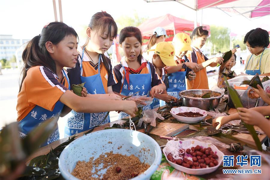 6月23日，孩子們在活動現(xiàn)場參加包粽子比賽。 當日，全國最大的易地生態(tài)移民扶貧集中安置區(qū)寧夏吳忠市紅寺堡區(qū)舉行迎端午活動，邀請各鄉(xiāng)鎮(zhèn)的民間剪紙、刺繡藝人現(xiàn)場比拼傳統(tǒng)技藝，居民現(xiàn)場參與包粽子大賽，共迎端午節(jié)的到來。 新華社記者 王鵬 攝