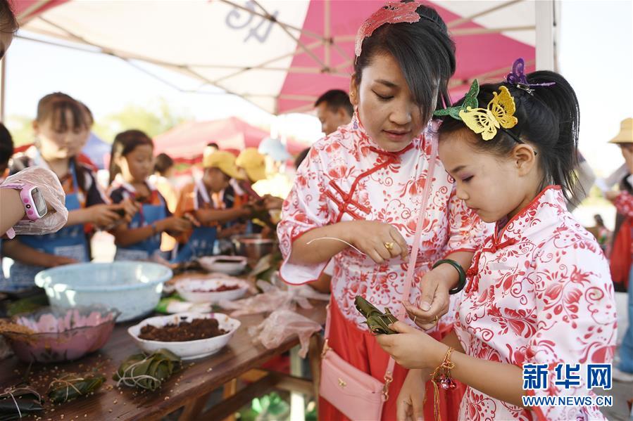 6月23日，孩子們在活動現(xiàn)場參加包粽子比賽。 當日，全國最大的易地生態(tài)移民扶貧集中安置區(qū)寧夏吳忠市紅寺堡區(qū)舉行迎端午活動，邀請各鄉(xiāng)鎮(zhèn)的民間剪紙、刺繡藝人現(xiàn)場比拼傳統(tǒng)技藝，居民現(xiàn)場參與包粽子大賽，共迎端午節(jié)的到來。 新華社記者 王鵬 攝