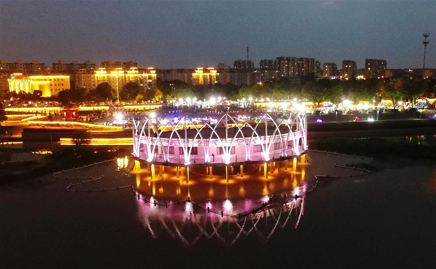 7月4日拍攝的江蘇省金湖縣荷花廣場(chǎng)夜景（無(wú)人機(jī)照片）。 江蘇省淮安市金湖縣位于江蘇省中部，境內(nèi)白馬湖、寶應(yīng)湖、高郵湖三面環(huán)繞。近年來(lái)，當(dāng)?shù)匕l(fā)揮其獨(dú)特的地理區(qū)位優(yōu)勢(shì)，打造出金湖龍蝦廣場(chǎng)、堯帝古城小吃街、荷花廣場(chǎng)便民服務(wù)點(diǎn)等一批特色區(qū)域，豐富當(dāng)?shù)厝罕娨股睢?新華社發(fā)（孟德龍 攝）