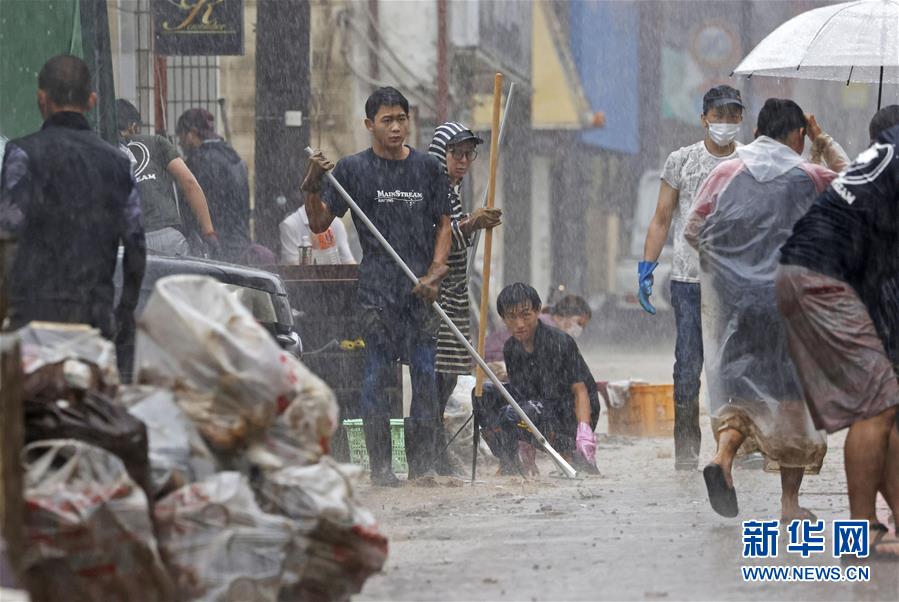 7月7日，日本熊本縣人吉市居民在大雨中清理街道。 受停滯的梅雨鋒面影響，日本九州地區(qū)北部7日繼續(xù)遭遇強(qiáng)降雨天氣。迄今，九州因暴雨引發(fā)的洪水泛濫、山體滑坡造成的死亡人數(shù)升至55人，另有13人失蹤。 新華社/共同社