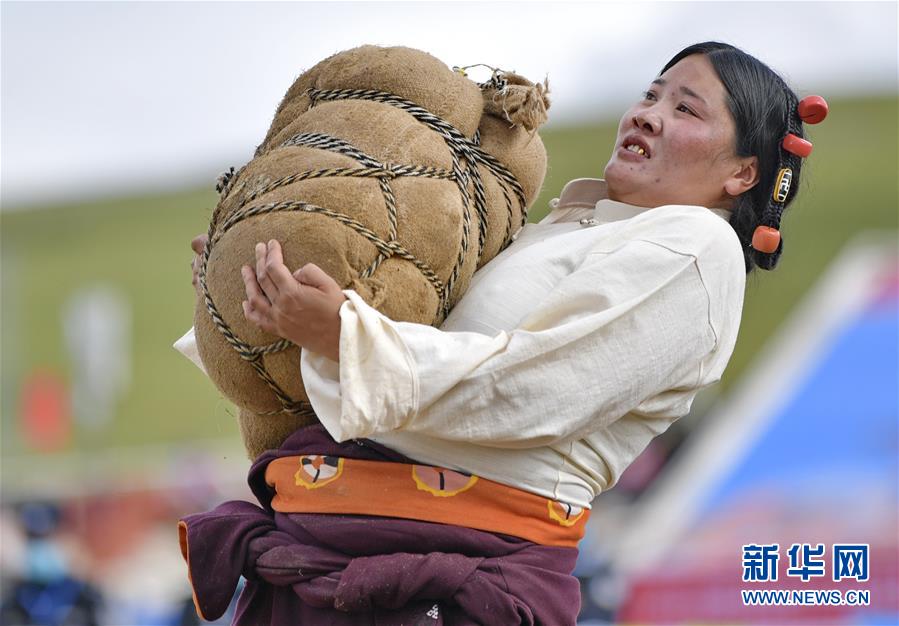 8月10日，一名婦女在參加抱石頭比賽。當(dāng)日，2020年那曲羌塘恰青格薩爾賽馬藝術(shù)節(jié)在西藏那曲市格薩爾賽馬場(chǎng)開幕，來自那曲各縣區(qū)的農(nóng)牧民在賽馬場(chǎng)參加了抱石頭比賽和押加賽。新華社記者 張汝鋒 攝