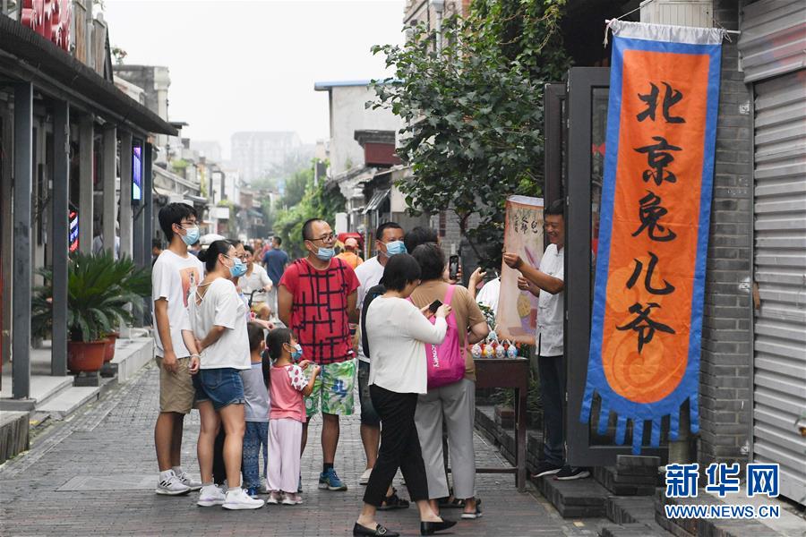在北京楊梅竹斜街，游客在一家經(jīng)營傳統(tǒng)老北京手工藝品“兔兒爺”的小店參觀（8月17日攝）。  新華社記者 鞠煥宗 攝