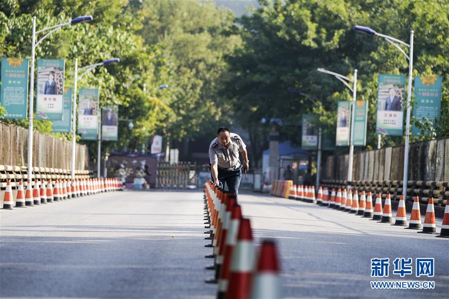 8月26日，在重慶市江北中學(xué)，安保人員在大門口擺放隔離樁。 新華社發(fā)（秦廷富 攝）