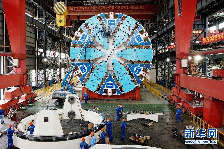 10月15日，在隧道股份上海隧道工程有限公司機械制造分公司生產(chǎn)車間，工人在對“騏躍”盾構機進行安裝調試（無人機照片）。 近日，由隧道股份上海隧道工程有限公司自主研發(fā)制造的超大直徑盾構機“騏躍”在上海浦東成功調試下線。“騏躍”整機總重約為3200噸，總長約為99米，其中主機長度約為16米，刀盤切削直徑達14.05米。 新華社記者 方喆 攝