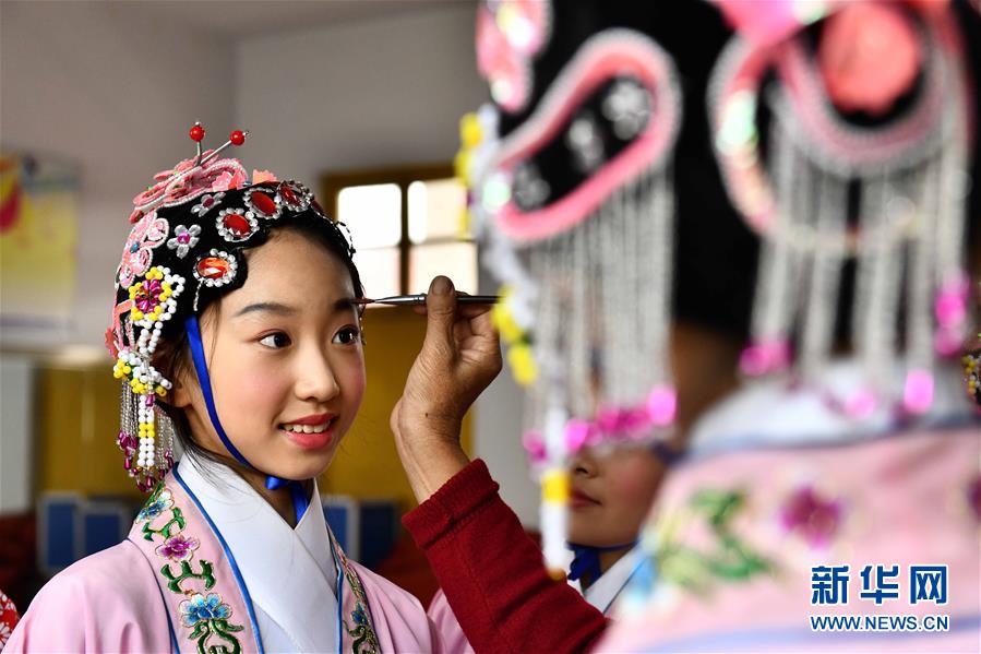 10月28日，在棗莊市臺兒莊區(qū)西關(guān)小學(xué)，文藝志愿者給小學(xué)員描眉。為傳承中華優(yōu)秀傳統(tǒng)文化，近年來山東省棗莊市臺兒莊區(qū)依托新時代文明實踐中心三級網(wǎng)絡(luò)，組織文藝志愿者作為校外輔導(dǎo)員，推動京劇、豫劇、柳琴戲、黃梅戲等優(yōu)秀傳統(tǒng)戲劇進(jìn)校園，讓小學(xué)員們體驗戲曲文化魅力。新華社記者 郭緒雷 攝