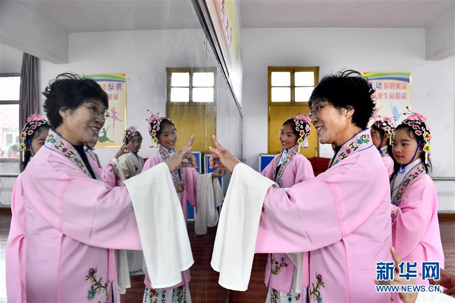 10月28日，在棗莊市臺兒莊區(qū)西關(guān)小學(xué)，文藝志愿者張鳳云在指導(dǎo)小學(xué)員練身段。新華社記者 郭緒雷 攝