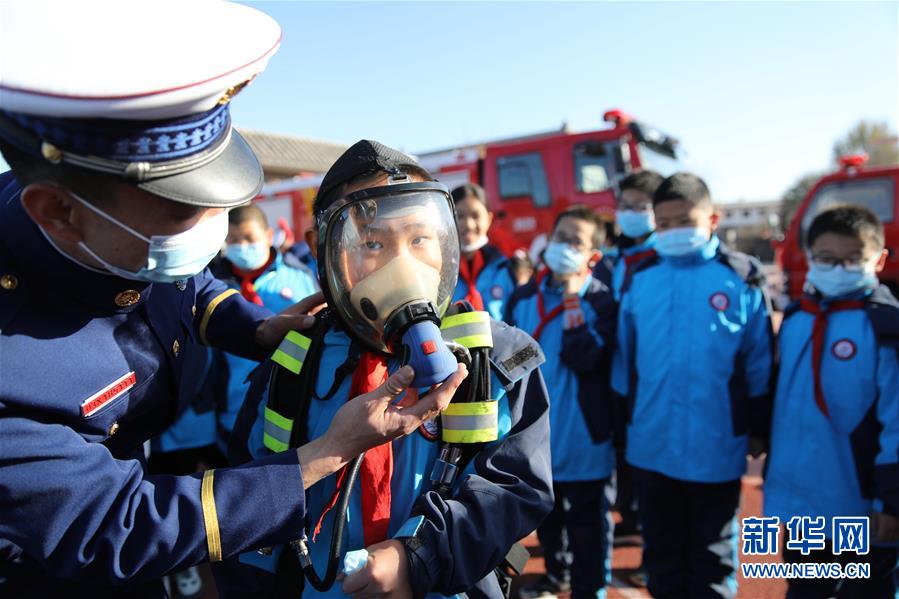 11月3日，在承德市雙橋區(qū)普寧小學，學生在消防救援人員指導下體驗使用正壓式空氣呼吸器。 當日，河北省承德市雙橋區(qū)消防救援大隊與普寧小學聯(lián)合開展消防進校園安全互動體驗教育活動。學生們通過體驗救生設備、安全使用消防器材等，在互動活動中學習消防知識，提升自救能力，迎接“119消防宣傳日”。 新華社發(fā)（劉環(huán)宇 攝）