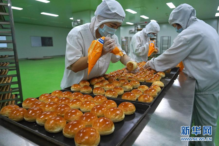 資溪縣面包食品產(chǎn)業(yè)城內(nèi)一家面包企業(yè)的工人在制作面包（11月11日攝）。近年來，江西省資溪縣通過建設(shè)面包食品產(chǎn)業(yè)城、舉辦面包文化節(jié)、構(gòu)建面包全產(chǎn)業(yè)鏈等舉措，帶動(dòng)當(dāng)?shù)厝罕娫鍪罩赂?。?jù)了解，資溪縣12.6萬人口中有近5萬人從事面包及相關(guān)產(chǎn)業(yè)，有“中國(guó)面包之鄉(xiāng)”稱號(hào)。新華社記者 萬象 攝