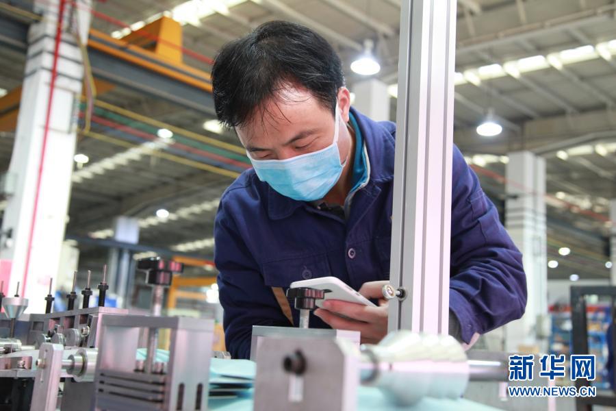 2月21日，機械工程師吳科龍在國機智能口罩機生產車間調試口罩機。新華社發(fā)