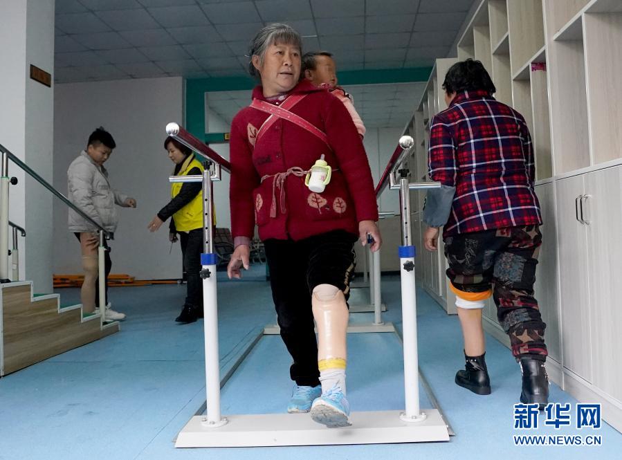 11月25日，來自織金縣中寨鎮(zhèn)水頭村的張胡敏老人背著孫子在康復(fù)中心進(jìn)行訓(xùn)練。貴州省畢節(jié)市織金縣積極推廣中央專項(xiàng)彩票公益金助殘項(xiàng)目，自2013年以來，開展為全縣殘疾人免費(fèi)安裝假肢活動(dòng)，并負(fù)責(zé)其康復(fù)訓(xùn)練，目前已有近300人受益。新華社記者 王毓國 攝