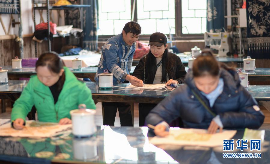 12月1日，在丹寨縣萬達(dá)小鎮(zhèn)歐報(bào)浪蠟染體驗(yàn)館，王方周（左二）在指導(dǎo)游客體驗(yàn)畫蠟畫。今年40歲的王方周是貴州省黔東南苗族侗族自治州丹寨縣排調(diào)鎮(zhèn)排聳村人，自幼喜歡繪畫和書法，對(duì)傳統(tǒng)蠟染制作手工藝也有著濃厚興趣。2016年8月，在外打工的王方周返鄉(xiāng)與人合作創(chuàng)辦了千年傳蠟染制作坊。后來，他們又在丹寨萬達(dá)旅游小鎮(zhèn)開辦歐報(bào)浪蠟染體驗(yàn)館。蠟染制作坊和蠟染體驗(yàn)館在今年已接待游客6000多名，創(chuàng)收30多萬元，也為當(dāng)?shù)匾椎胤鲐毎徇w安置點(diǎn)的13名村民提供月收入在2000元左右的就業(yè)崗位。王方周說，帶動(dòng)更多的群眾增收致富，傳承傳統(tǒng)手工藝，這就是我們創(chuàng)辦蠟染制作坊的初衷。新華社記者 楊楹 攝