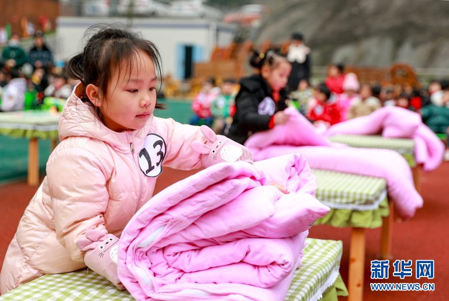 12月21日，四川省華鎣市清溪路幼兒園的小朋友在參加疊被子比賽。當(dāng)日，華鎣市清溪路幼兒園開展以“生活自理，快樂自立”為主題的幼兒生活技能大賽。幼兒園的小朋友們參加了疊被子、疊衣服、穿鞋子、剝熟雞蛋及整理書包等項(xiàng)目的比賽。比賽旨在培養(yǎng)孩子們的生活自理能力和良好的生活習(xí)慣。新華社發(fā)（邱海鷹 攝）