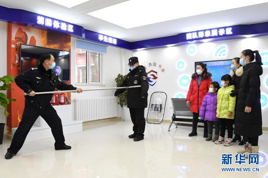 1月10日，在北京市公安局海淀分局永定路派出所第三社區(qū)警務(wù)工作站展示區(qū)，社區(qū)民警屈超直（左一）與安保人員向社區(qū)居民展示警用裝備的用法。當(dāng)日是首個中國人民警察節(jié)，在做好疫情防控的前提下，北京市公安局海淀分局永定路派出所第三社區(qū)警務(wù)工作站舉辦警務(wù)開放日活動。社區(qū)居民在警務(wù)工作站展示區(qū)通過社區(qū)民警的介紹了解防盜、防詐騙、禁毒等知識。新華社記者 任超 攝