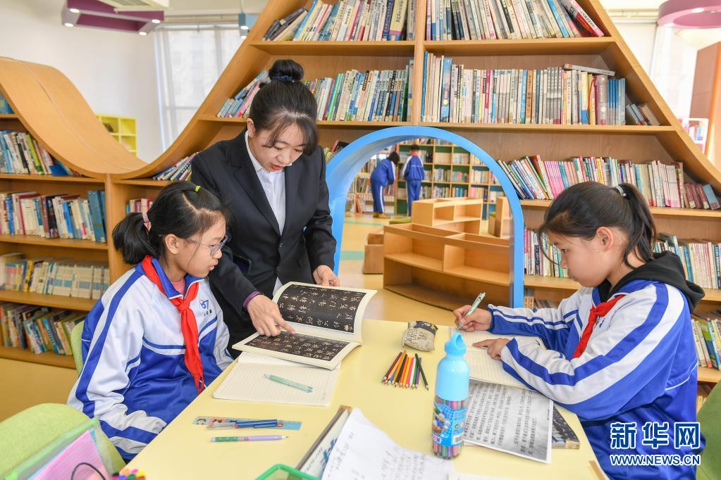 　　3月25日，在長春市第八十七中學(xué)圖書館，小學(xué)部教師孫銘輔導(dǎo)學(xué)生閱讀書籍。　　長春市第八十七中學(xué)小學(xué)部從2018年開始，探索引導(dǎo)學(xué)生用繪畫加文字的形式完成語文閱讀摘抄作業(yè)，在不額外增加學(xué)生作業(yè)負(fù)擔(dān)的前提下，培養(yǎng)學(xué)生的閱讀習(xí)慣。　　新華社記者 張楠 攝